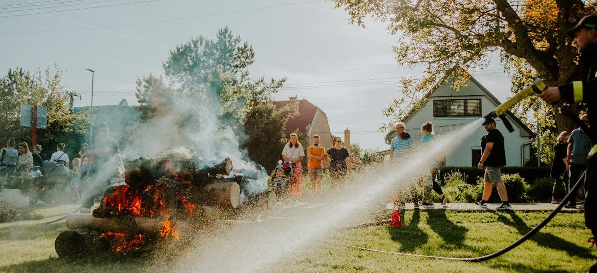 Firefighter showcases safety techniques on a controlled fire at a community event in the park.