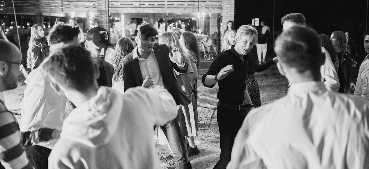 Black and white photo of people enjoying nightlife dancing under string lights.